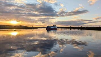 Corrib princes touristic boat cruise on Corrib river at sunset with sky reflection in water, nature background, Galway, Ireland photo