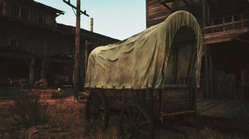 A rustic covered wagon in a serene field beside a charming building video