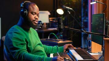 Professional artist writes new verses for a song in home studio, producing new music with mixing console and pc software. Composer works with audio equipment and tools, recording tunes. Camera A. photo