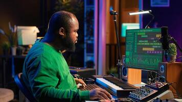 Audio technician works with recording tools in his home studio, using mixing console and pre amp knobs to add sound effects on tracks. Composer editing new tunes in post production. Camera A. photo