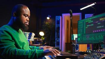Creative songwriter recording new tracks with microphone and midi controller, playing piano notes in home studio. Skilled musician composing music with electronic keyboard and stereo gear. Camera B. photo