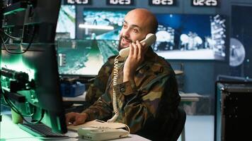 Military officer in command post receiving telephone call while looking at intel files. Intelligence specialist reading opponents strategy mission case file and talking on phone, camera A photo