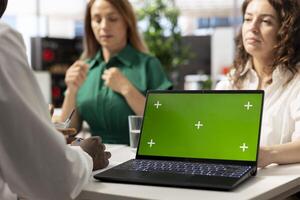 HR managers using green screen laptop to find best talent to fill open company position. Human resources coworkers hired to assess skills of candidate, using mockup notebook photo