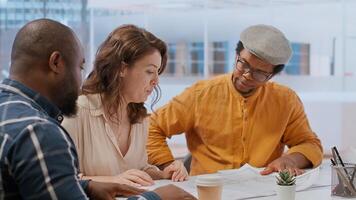 Professional clients and their real estate agent evaluating blueprints for the high class modern space, discussing leasing contract terms before signing. Startup business development. Camera B. photo