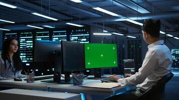 Programmer in data center managing and maintaining databases using mockup PC, ensuring data integrity and security. Expert updating server room systems using green screen computer, camera B photo