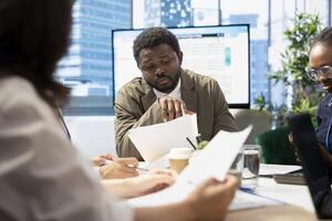 Business professionals engage in a strategy session for a new project, utilizing documents with data analytics to develop innovative solutions to improve the market presence. Conference table. photo
