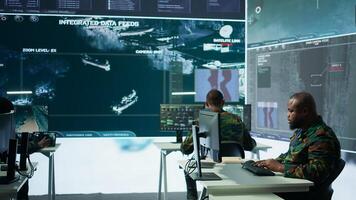 Military crew in a high tech operations command post managing information from radar cctv systems, real time data to support defense missions. Army protocols for national security. Camera B. photo