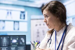 Woman physician reading x ray diagnostics for a patient in medical office, doing a test results scan interpretation to help person with disease. Providing treatment and advice for recovery. photo