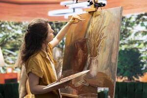 Skilled woman painting an artwork with colorful paints mixed on a palette, creating a beautiful creative paintwork with a certain painting technique in her atelier. Artist mixing watercolor. photo