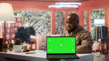 Young entrepreneur reviewing budget balance reports at his home desk, using mockup copy space display on a tablet. Businessman reviews monthly sales to obtain new investment funds. Camera B. photo
