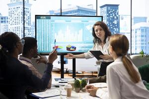 Marketing team attending an information sharing meeting to verify updates on regulatory changes or industry standards. Business associates reviewing data infographics on interactive board. photo