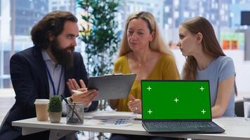 Financial advisor presenting financial guide to customers using green screen laptop. Agent in office assisting clients with investment portfolio management helped by chroma key notebook, camera B photo