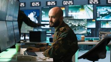 Man looking at screens in military HQ base housing operational missile defense system designed to intercept ballistic rockets. Special forces expert using tracking gear and radar systems, camera A photo
