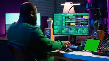 Artist producer creating new music with mix and master techniques, using a screen with copy space layout. Skilled audio engineer editing tracks in post production, digital audio software. Camera A. photo