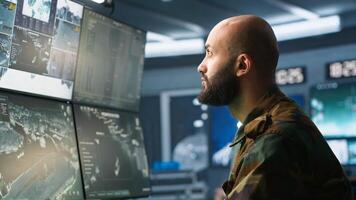 Soldier doing patriotic duty in military HQ base, gathering information on enemy troops. Officer using high tech monitoring gear to do assessment of enemy vulnerabilities, camera A photo