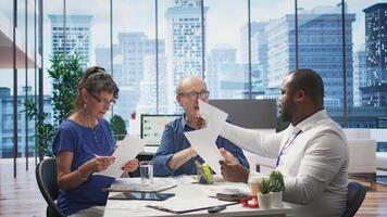 Mature couple meeting with a financial expert to develop a detailed retirement plan, focusing on savings and long term financial security. Clients discussing with broker in office. Camera B. photo