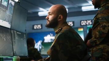 Soldier doing tasks in military base, doing surveillance with digital radar equipment, operating missile systems. Middle Eastern man monitoring army HQ CCTV for any unauthorized activity, camera A photo