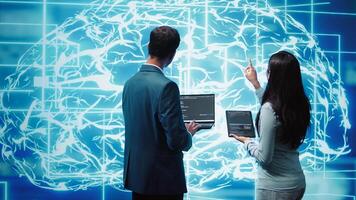 Team of admins using tablet and laptop to maintenance artificial intelligence neural networks. Teamworking IT staff members using AI system aiding in processing and transmitting information, camera B photo