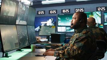 Army telecommunication systems operator providing combat support using gathered information on enemy troops. Military dispatcher managing communications networks in base of operations, camera B photo