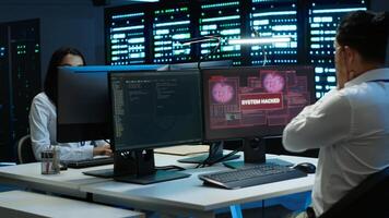 Team of programmers in server hub try to protect hardware from hacker attack stealing sensitive information. Data center cybersecurity division coworkers fight virus during security breach, camera A photo