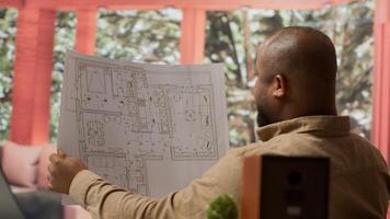 Corporate owner planning an office interior design renovation, reviewing blueprints and collaborating with contractors to create a modern workspace. Evaluating property sketches at home. Camera A. photo