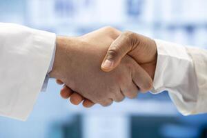 Diverse medics shaking hands after a successful treatment plan collaboration during a meeting with licensed physicians. Doctors with expertise doing a handshake for great partnership. Close up. photo