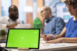 Financial counseling discussion with a tablet showing green screen on display, old people discussing with a banker to find a pension plan option for retirement stability. Close up. photo