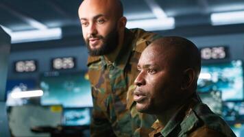 Army unit working in governmental facility next to colleague, operating surveillance monitoring tech with digital equipment. African american man doing job in base of operations, camera A photo