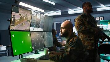 Army soldier looking at chroma key screens in command center housing operational missile defense system designed to intercept ballistic rockets. Specialist using mockup tracking gear, camera B photo