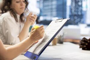 HR employee using highlighter marker on paperwork, ensuring candidate possesses skills needed to fulfil role. HR manager highlighting text on documents, evaluating applicant photo