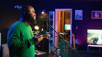 Singer performing his new track creation on a microphone, manipulates his audio files recordings with mixing and mastering techniques. Artist composer operates on stereo equipment. Camera B. photo