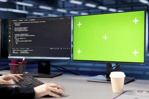 Lines of code running on isolated screen computers displays in data center, used for troubleshooting rackmounts in server rows. Close up of programming scripts on chroma key PC monitors in server hub photo