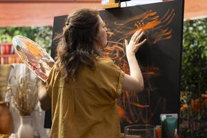 In an art studio, painter uses watercolor paint to create a finger painted masterpiece. Creative talented artist showing her inspiration to create a rustic colorful artwork with handprints. photo