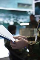 Serviceman inspecting special operation details from the top secret case file, reading important battlefield information to ensure defense mission success. Trooper works in command center. Close up. photo
