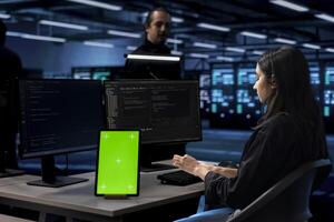 Engineer in data center uses isolated screen tablet to update systems, protecting servers from software vulnerabilities. IT expert uses chroma key device to look for errors affecting servers photo