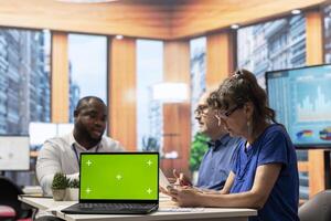 Financial broker and senior couple exploring retirement plans options next to green screen on laptop, ensuring stability for retired people. Advisor offering his professional advice. photo
