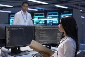 IT supervisor verifying data center gear documentation files, ensuring proper configurations and procedures. Server hub IT professional reading performance reports and conducting analysis photo
