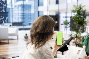 HR expert discussing with woman, vetting applicants to ensure skills match role needs, using mockup mobile phone. Headhunter chatting with person coming for interview, using chroma key smartphone photo