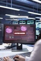 Engineer in server hub frightened by hacker passing company firewall and stealing sensitive user data. Afraid man panicking after seeing security breach notification on computer in data center photo