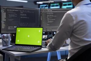 Engineer using green screen laptop to do maintenance on high bandwidth, dedicated game servers used to accommodate incoming traffic of online users joining from worldwide locations photo