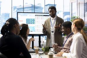 General manager sharing insight on annual infographics reports in enterprise meeting, providing initiatives to enhance operational performance metrics. Group of business associates exchange ideas. photo