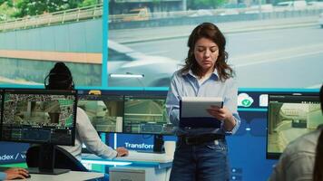 Portrait of woman supervisor overseeing the traffic surveillance monitoring activity in a observation room, CCTV satellite system. Diverse team of people handling license plate reading. Camera A. photo
