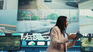 Indian supervisor gather intelligence on cargo delivery logistics by following the route through street traffic via satellite map. Manager works with her team in control center. Camera B. photo