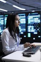 Manager in server hub using computer to find firewall misconfigurations affecting rackmounts performance. Supervisor checking systems bottlenecks leading to sluggish data transfer rates photo