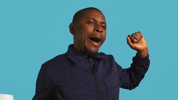 Headshot portrait of security agent drinking coffee to stop yawning while securing assigned post, studio background. Close up shot of guardian consuming caffeinated beverage, camera B photo