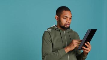 Upbeat man adding payment method on online website using tablet. Person thrilled to do internet shopping using device, typing debit card data, isolated over studio background, camera A photo