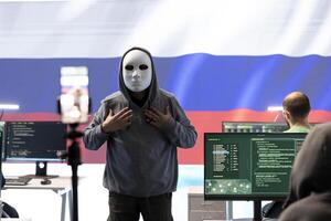 Anonymous hacker expert in a russian hacking high tech office, digital threats and political espionage. Inflicting cyber terror, propaganda and crisis management in information war. photo