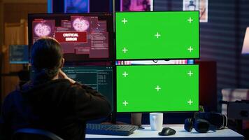 Scammer hacking using green screen PC and getting critical error notification while trying to infiltrate banking systems. Hacker runs script on chroma key display, failing to breach firewall, camera A photo