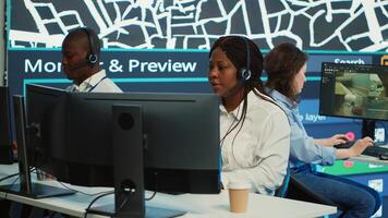 Diverse team of operators providing order tracking updates to clients, following delivery trucks around the city via gps coordinates and satellite map. Using surveillance CCTV footage. Camera A. photo