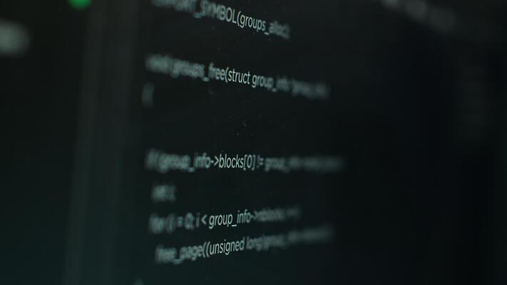 Extreme close up shot of hacking code running on computer system monitors attacking firewalls. Programming scripts shown on PC screen used by cyber criminals to breach security